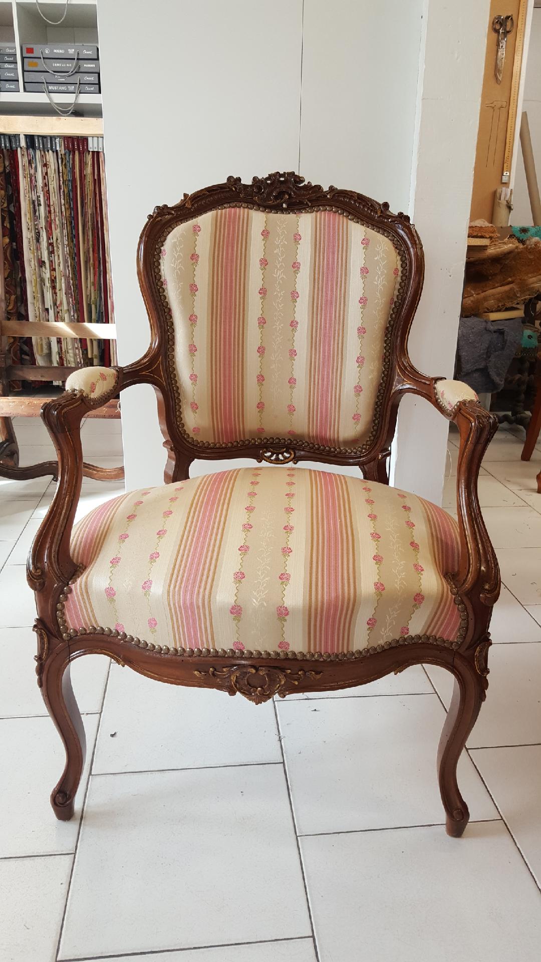 Fauteuil Louis XV en bois sculpté, tapissé d'un jacquard à bandes roses et guirlandes de roses, dans l'atelier de L'Atelier Artisanal